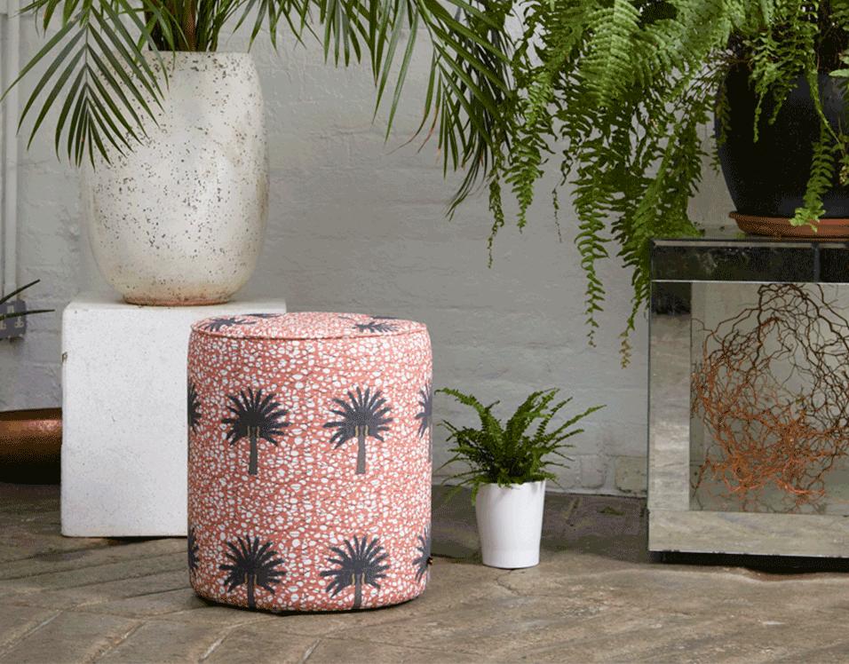 Bright baby pink African print pouffe with large green and brown tropical palm tree  